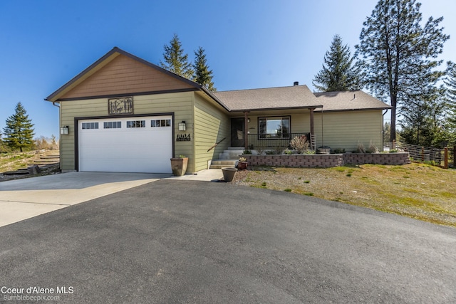 ranch-style home with driveway, fence, a porch, and a garage