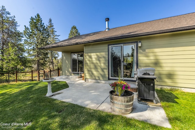 rear view of property featuring fence, a patio area, and a lawn