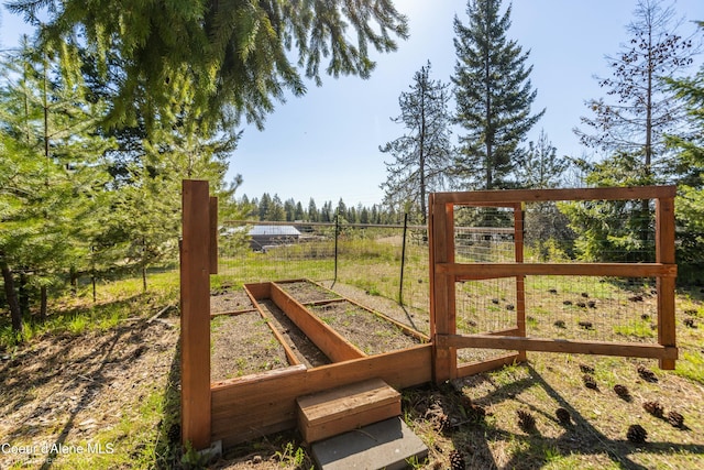 view of gate with fence and a vegetable garden