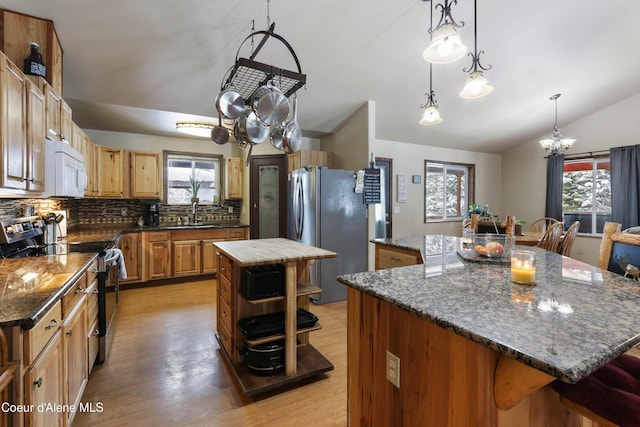 kitchen featuring appliances with stainless steel finishes, backsplash, a center island, decorative light fixtures, and vaulted ceiling