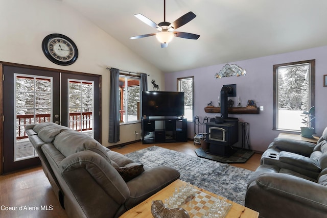 living room featuring hardwood / wood-style floors, high vaulted ceiling, ceiling fan, and a wood stove