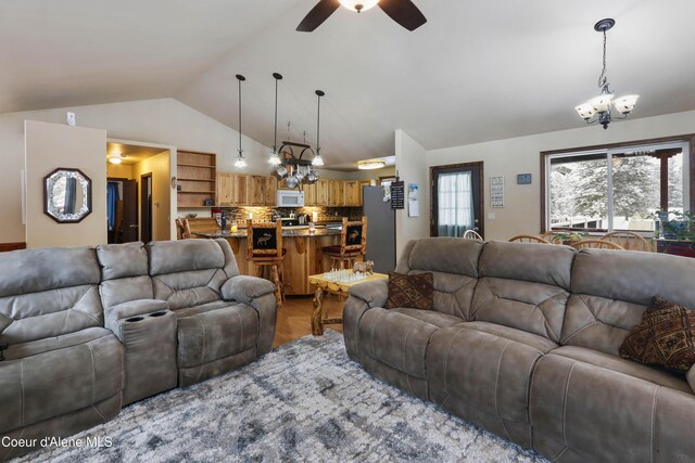 living room with vaulted ceiling, ceiling fan with notable chandelier, and light wood-type flooring