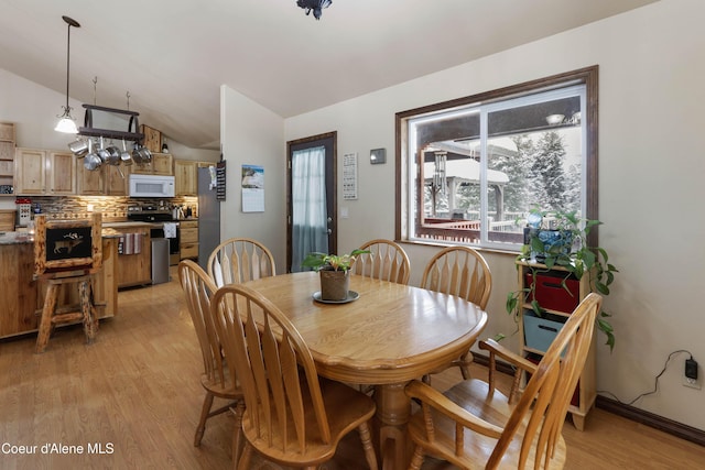 dining space featuring vaulted ceiling and light hardwood / wood-style flooring