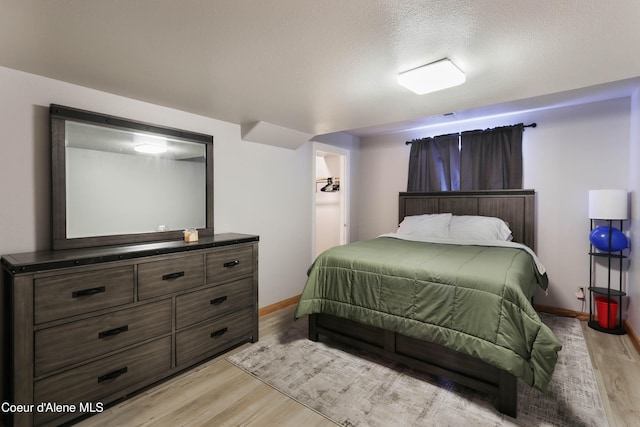 bedroom featuring a textured ceiling and light hardwood / wood-style flooring