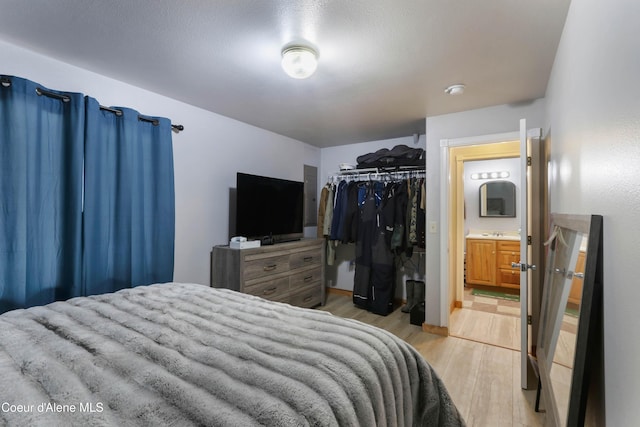 bedroom featuring ensuite bath, light hardwood / wood-style flooring, and a closet