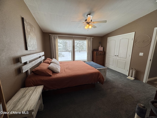 bedroom with ceiling fan, lofted ceiling, dark carpet, and a textured ceiling