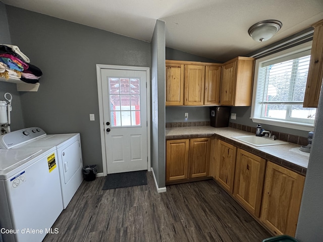 kitchen featuring lofted ceiling, dark hardwood / wood-style flooring, washer and clothes dryer, and sink