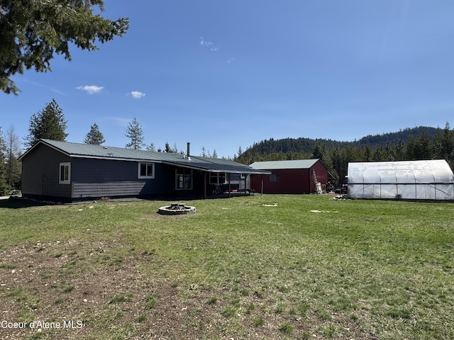 4058 W Seasons Rd, Rathdrum, ID 83858 - view of yard with an outbuilding, an outdoor fire pit, and a wooded view