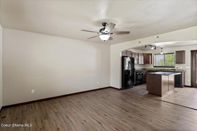 13043 N Zodiac Loop, Rathdrum, ID 83858 - kitchen with black appliances, wood finished floors, a kitchen island, and a ceiling fan