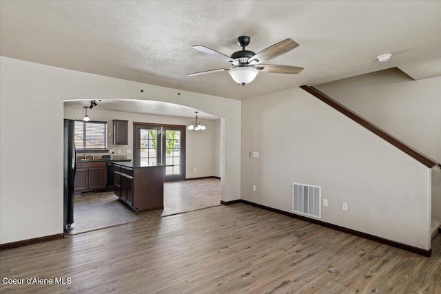 13043 N Zodiac Loop, Rathdrum, ID 83858 - unfurnished living room with wood finished floors, a ceiling fan, arched walkways, and baseboards