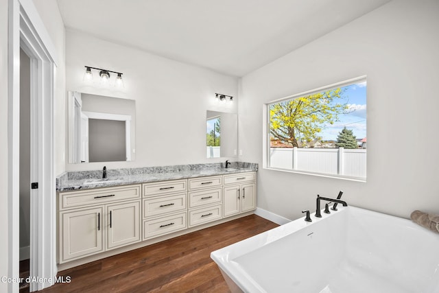 1225 W Orchard Ave, Hayden, ID 83835 - bathroom featuring a freestanding bath, double vanity, wood finished floors, and a sink