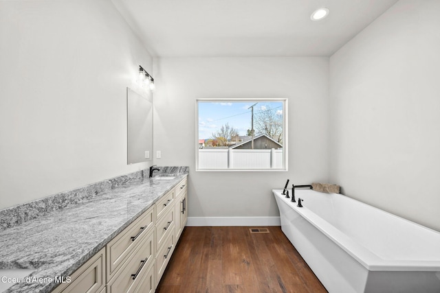 1225 W Orchard Ave, Hayden, ID 83835 - bathroom featuring a freestanding bath, wood finished floors, visible vents, vanity, and baseboards
