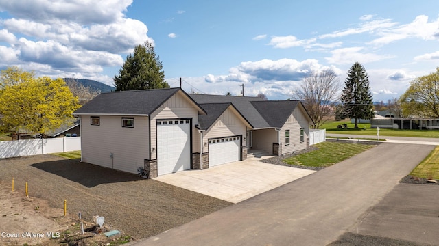 1225 W Orchard Ave, Hayden, ID 83835 - view of front of home with fence, concrete driveway, board and batten siding, an attached garage, and stone siding
