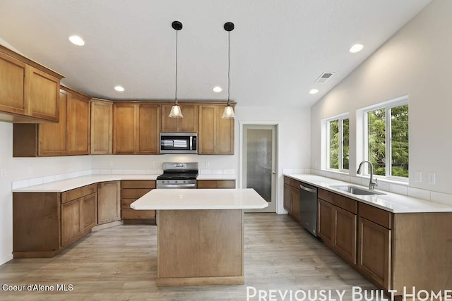 kitchen featuring appliances with stainless steel finishes, brown cabinets, visible vents, and a sink