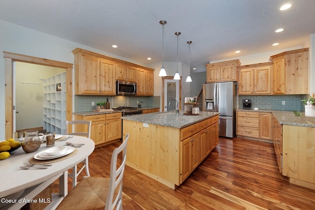 kitchen featuring light stone counters, dark wood-style flooring, stainless steel appliances, light brown cabinets, and a sink