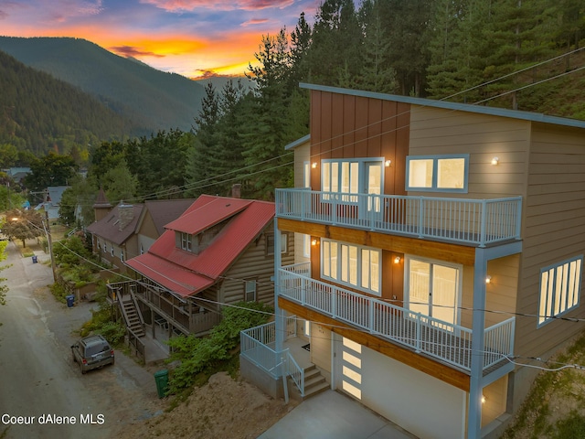 back house at dusk featuring a mountain view, a garage, and a balcony