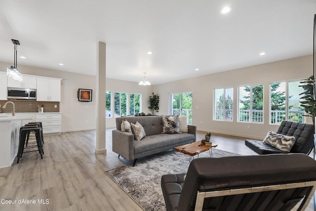 living room featuring an inviting chandelier, sink, and light hardwood / wood-style floors