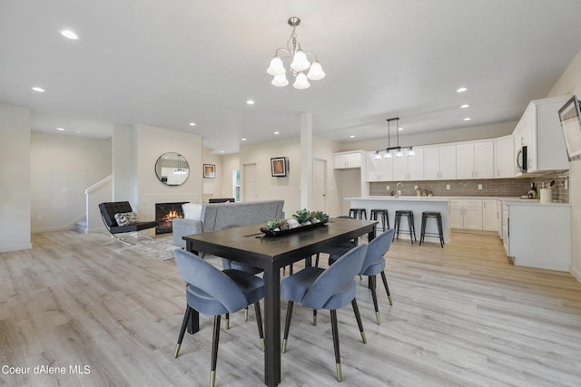 dining area with sink, a notable chandelier, and light hardwood / wood-style floors