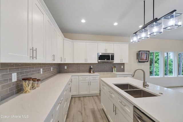 kitchen featuring pendant lighting, white cabinetry, sink, decorative backsplash, and light hardwood / wood-style floors