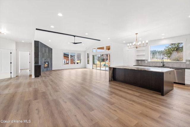 kitchen featuring a fireplace, sink, white cabinets, a center island, and stainless steel dishwasher