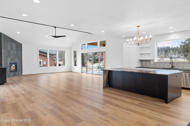 kitchen with a spacious island, plenty of natural light, a tiled fireplace, and light hardwood / wood-style flooring