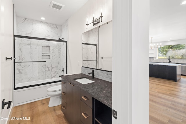 full bathroom with toilet, combined bath / shower with glass door, wood-type flooring, vanity, and backsplash