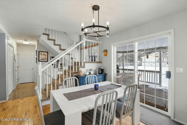 dining area with an inviting chandelier, a textured ceiling, and light wood-type flooring