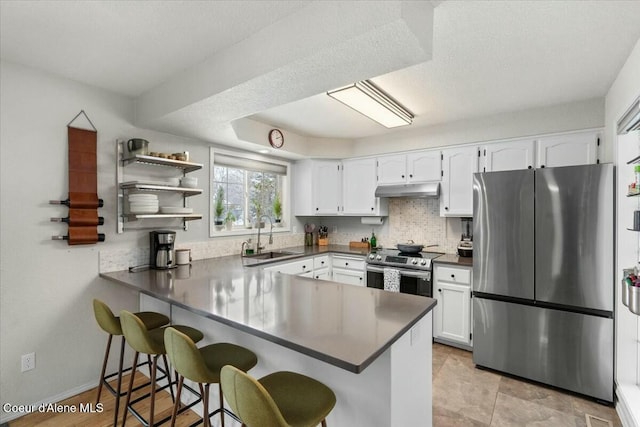 kitchen with stainless steel appliances, kitchen peninsula, sink, and white cabinets