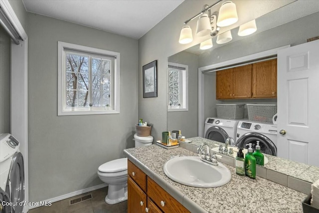 bathroom with vanity, toilet, tile patterned flooring, and washer and dryer