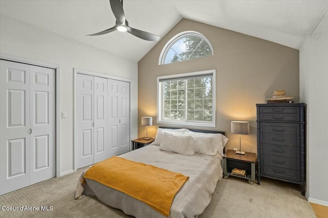 carpeted bedroom with ceiling fan, lofted ceiling, and two closets