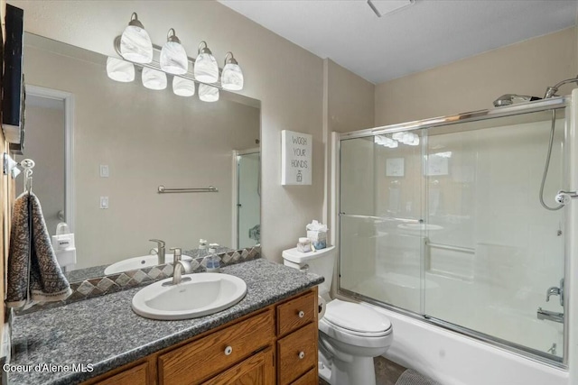 full bathroom with enclosed tub / shower combo, vanity, and toilet