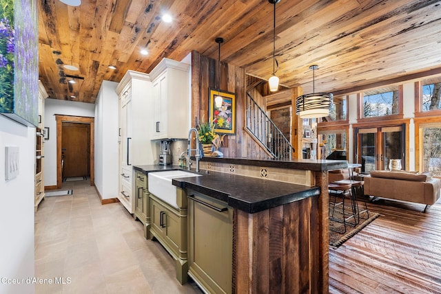 kitchen with sink, wooden ceiling, white cabinets, a kitchen bar, and pendant lighting