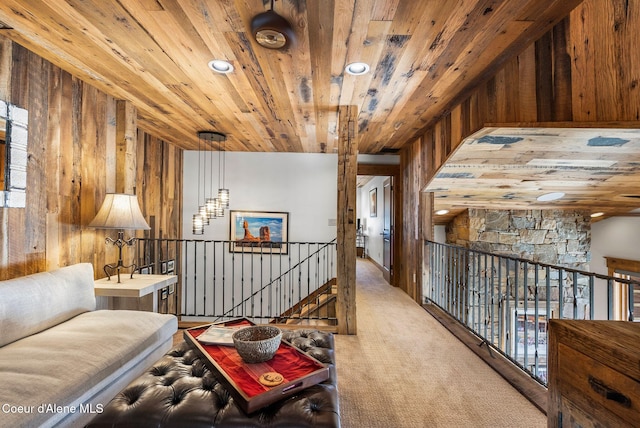 sitting room featuring wooden walls, wooden ceiling, and light colored carpet