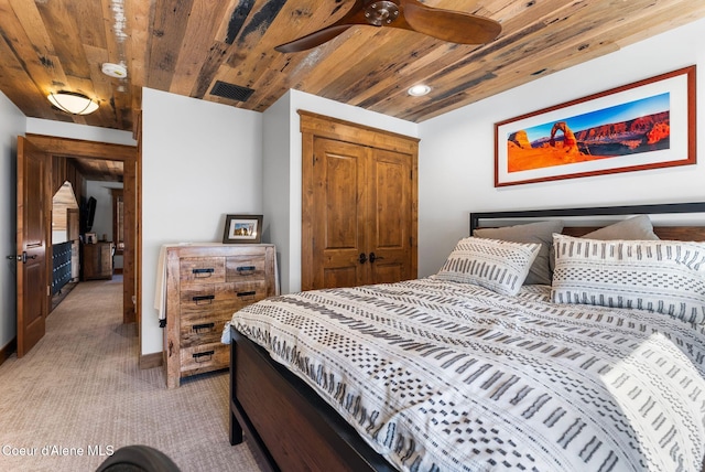 bedroom with a closet, light colored carpet, and wood ceiling
