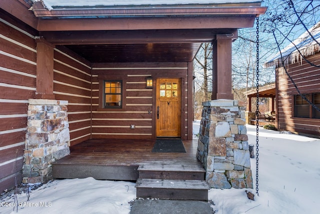 snow covered property entrance featuring a porch