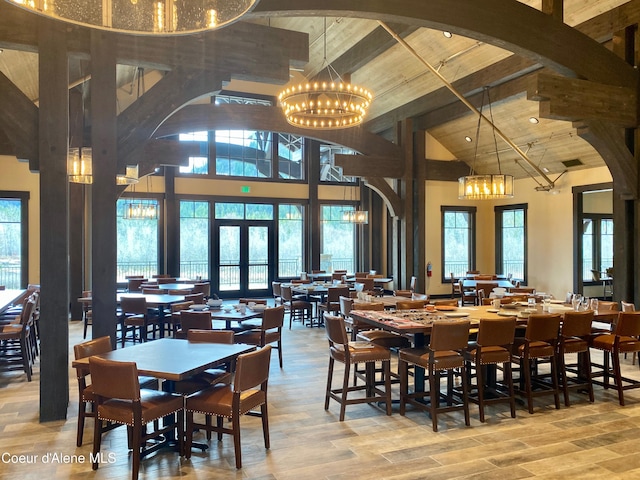 dining space with french doors, high vaulted ceiling, wood ceiling, light wood-type flooring, and an inviting chandelier