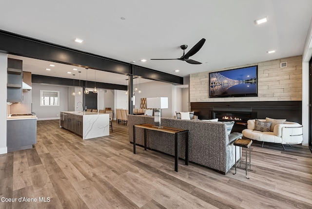 living room featuring sink, light hardwood / wood-style floors, and ceiling fan