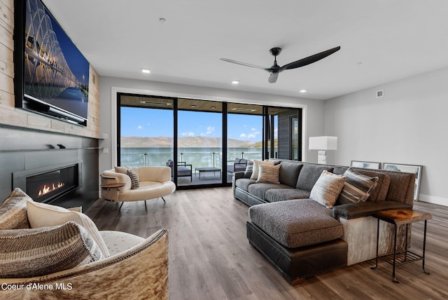 living room featuring hardwood / wood-style floors, a fireplace, and ceiling fan