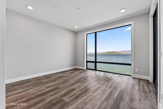 unfurnished room with hardwood / wood-style flooring and a water view