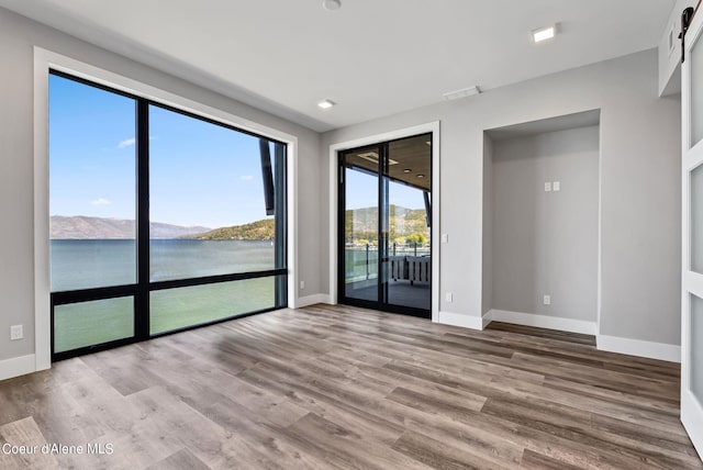 empty room with a water and mountain view and wood-type flooring
