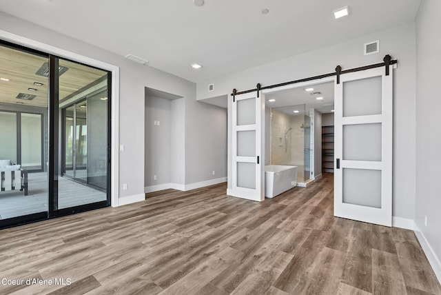 unfurnished living room with wood-type flooring and a barn door