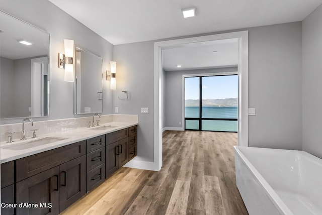 bathroom featuring vanity, a bath, hardwood / wood-style flooring, and a water view
