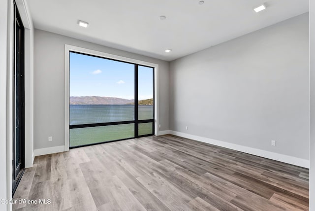 spare room with a water view and light hardwood / wood-style floors
