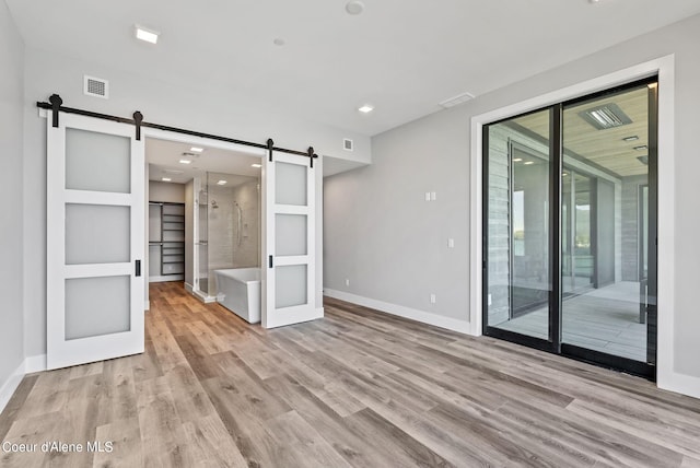 unfurnished room featuring a barn door and light wood-type flooring