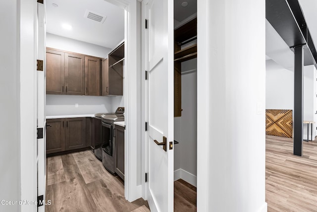laundry room with cabinets, washing machine and dryer, and light hardwood / wood-style floors