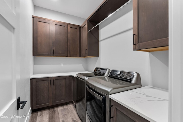 washroom with cabinets, washer and dryer, and light wood-type flooring