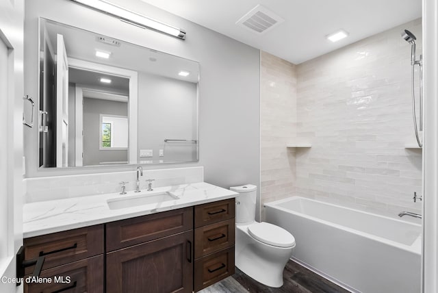 full bathroom with vanity, tiled shower / bath, hardwood / wood-style flooring, and toilet