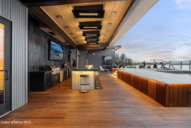 deck at dusk featuring exterior kitchen and a grill
