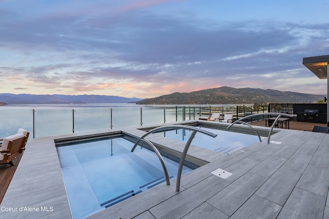 pool at dusk with a water and mountain view