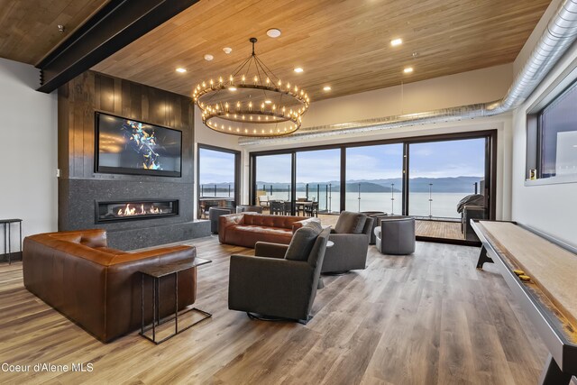 living room with wood ceiling, hardwood / wood-style flooring, beam ceiling, a large fireplace, and a chandelier